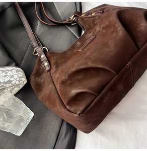 Detail of dark brown tote bag with vintage texture and gold ring strap connector