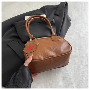 Détail du sac à main marron en cuir grainé avec un pendentif en forme de cœur