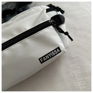 Close-up of white crossbody bag featuring black zipper and FANYISSA brand label