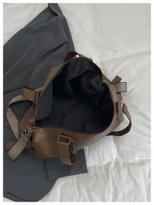 Detail of dark brown travel tote featuring woven strap and spacious interior lining