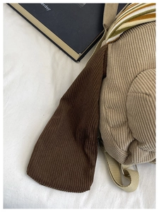 Detail of beige and brown corduroy backpack showing fabric texture and woven strap