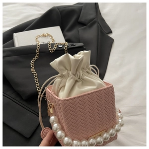 Detail view of pink woven bucket bag with pearl handle and cream drawstring liner