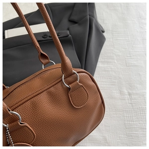 Gros plan du sac à main marron avec motif litchi, anneaux argentés et doubles anses