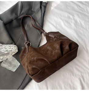 Detailed close-up of brown suede tote bag with metallic rings on a stylish office background
