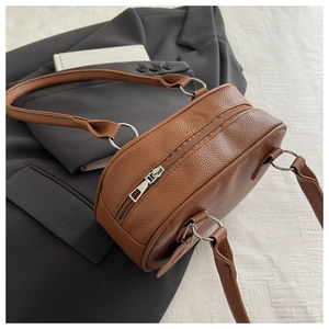 Détail du sac cylindrique en cuir marron avec texture litchi et pendentif en cœur