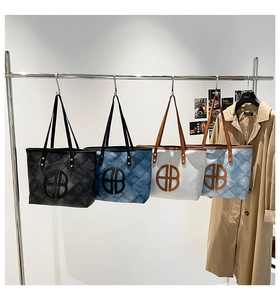 Close-up of quilted tote bags in black, denim blue, and white with metal logo detail