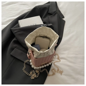 Pink woven bucket bag showing spacious interior with pearl handle and golden chain strap