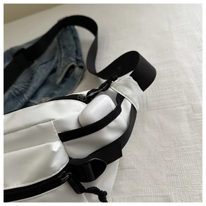 Detail of white nylon crossbody waist bag showing interior storage with earbuds case