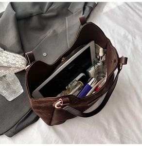 Macro shot of spacious suede tote bag interior with daily essentials on a cozy bed