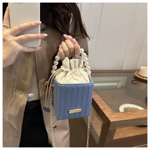 Detail of woven bucket bag with pearl handle and gray-blue drawstring interior