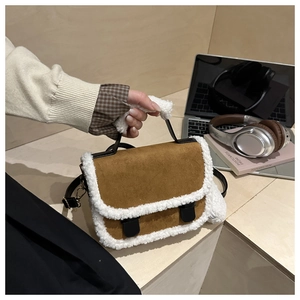 Detail of brown suede handbag with white faux fur trim and black leather buckles