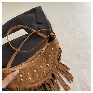 Detail of brown suede crossbody bag featuring retro gold rivets and long fringes