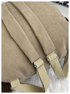 Detail of khaki corduroy backpack straps with adjustable silver metal buckles and texture