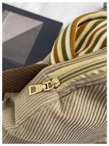 Detailed macro view of corduroy fabric texture and gold zipper on a chic backpack