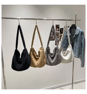Four corduroy hobo shoulder bags in black khaki grey and white hanging on a metal rack