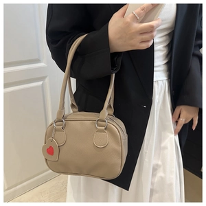 Detail of lychee pattern leather bowling bag with a red heart charm and double handles