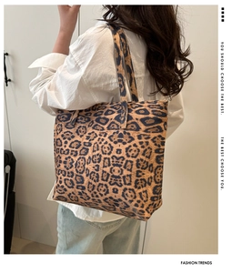 Detail view of large leopard print tote bag worn on shoulder over neutral attire