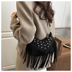 Detail of a black crescent shoulder bag featuring gold rivets and long fringe tassels