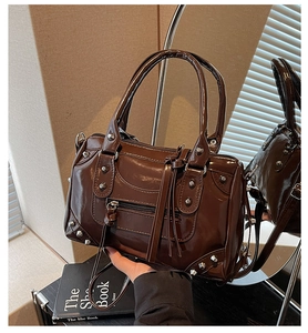 Dettaglio della borsa Boston marrone scuro lucida con borchie e nappe in pelle decorative