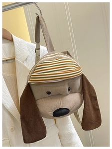 Detail view of corduroy puppy backpack featuring 3D floppy ears and a striped hat element