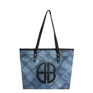 Blue denim patchwork tote bag with black circular embroidery and gold rivet straps