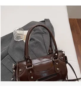 Dettaglio dei rivetti e della pelle lucida sulla borsa vintage marrone scuro