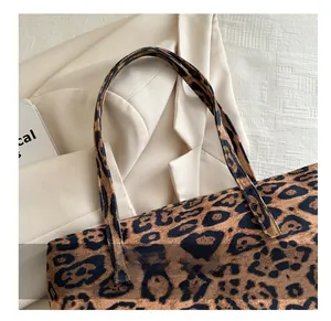 Close-up of leopard print tote bag texture and sturdy handle connection on beige blazer