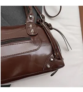 Dettaglio di borsa da moto lucida marrone scuro con rivetti e nappine in pelle