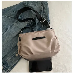Detail view of beige nylon crossbody bag featuring ruched side pockets and adjustable strap