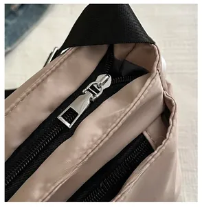 Close-up of durable smooth silver metal zipper and fine stitching on beige nylon bag
