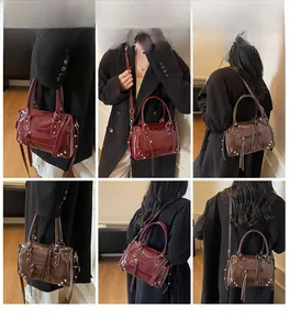 Dettaglio della borsa Boston vintage con borchie e nappe in rosso vino e marrone