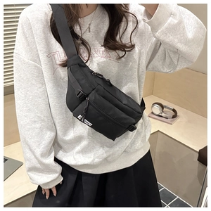 Detailed view of black nylon crossbody fanny pack worn by model in casual indoor setting