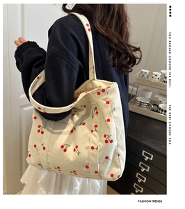 Détail du sac cabas en velours côtelé avec broderie cerise porté par le mannequin