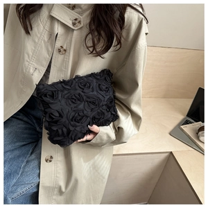Close-up of black 3D rose petal evening clutch bag held by model in a stylish setting