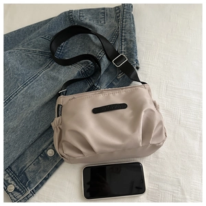 Macro shot of khaki nylon crossbody bag with adjustable strap and embossed detail