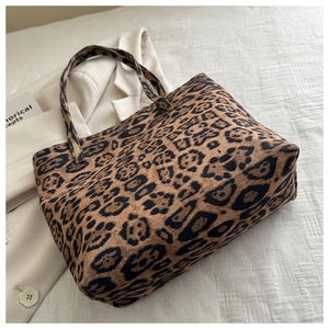 Detail of trendy leopard print tote bag with dual handles on a white textured background