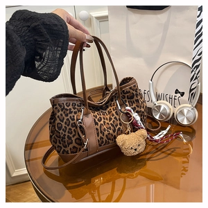Detail of leopard print suede bucket bag with plush bear charm and leather strap