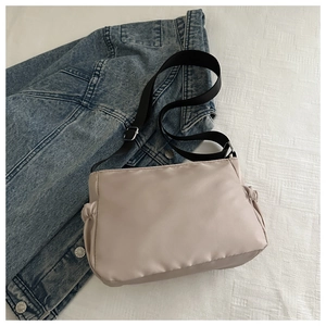 Detail of light beige nylon crossbody bag with side drawstring and adjustable strap