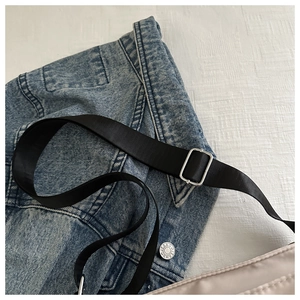 Close-up of adjustable black nylon strap with silver metal buckle on cream handbag