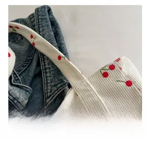Détail du sac cabas en velours côtelé blanc avec broderie cerise et texture douce
