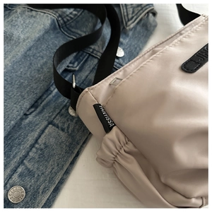 Detail of khaki nylon crossbody bag featuring waterproof fabric and adjustable strap