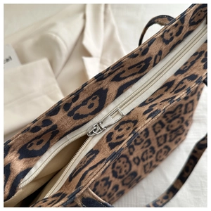 Detailed shot of top silver zipper and brown leopard print fabric on a stylish tote bag