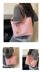 Pink tote bag detail with all-over M letter print and decorative metal pendant