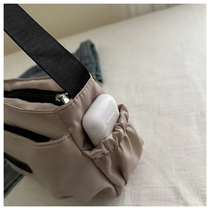 Detail view of khaki nylon bag featuring elastic side pocket for earphone storage