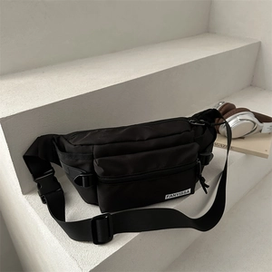 Minimalist black nylon crossbody sling bag with adjustable strap on a modern white background