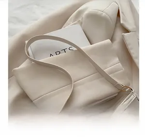 Detail shot of the wide cream faux leather shoulder strap on a matching blazer