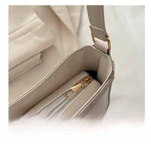 Detail of smooth golden zipper and lychee pattern texture on beige leather bag