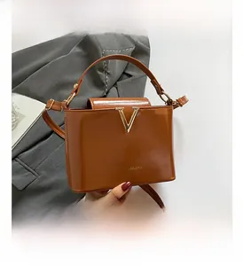 Detail of vintage brown crossbody bucket bag with golden V-clasp and fashion lettering