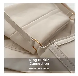 Macro detail of high-quality metal ring buckle and fine stitching on cream shoulder bag