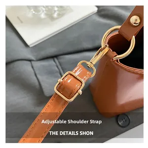 Close-up of adjustable brown leather strap with polished gold-tone metal hardware